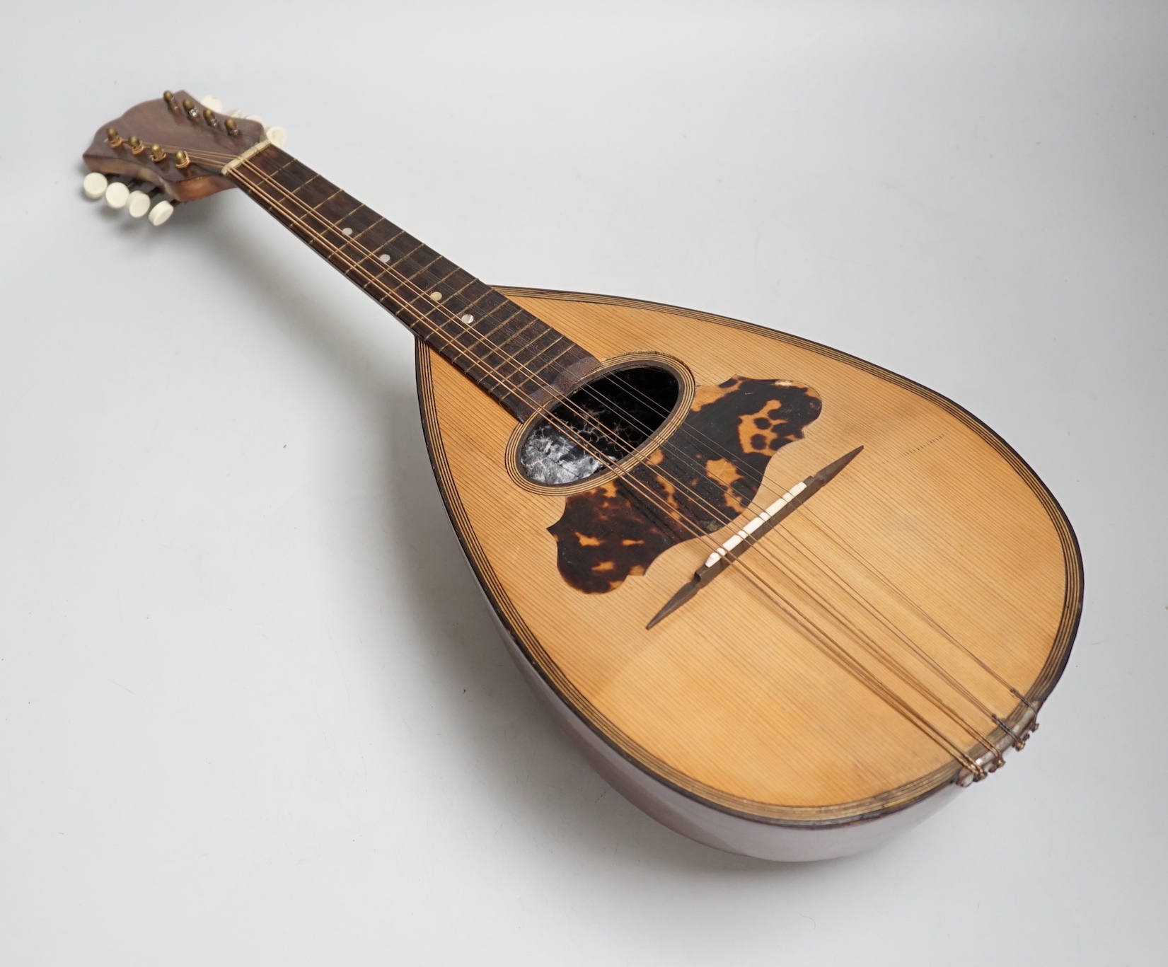 A cased mandolin with tortoiseshell detail, bone tuning pegs, 61cm long